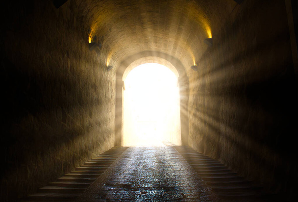 暗いトンネルの端を突き抜ける明るい黄色の輝く光 - 写真・画像