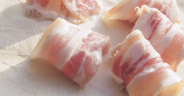 Bacon slices on cooking paper. Raw rolled bacon with spices. - 写真・画像