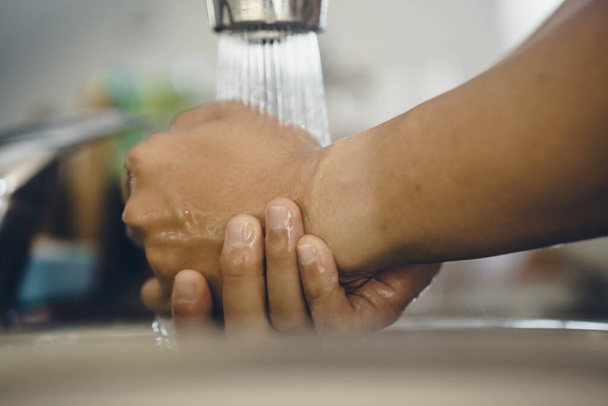 Zawsze należy zacząć od czystych rąk, aby zapobiec rozprzestrzenianiu się koronawirusu (Covid-19). Ujęcie azjaty myjącego ręce w domu. - Zdjęcie, obraz