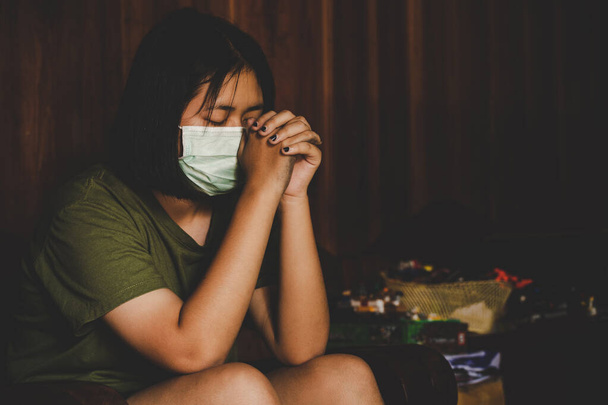 Chinois adolescent fille portant un masque pour protéger pm2.5 et Covid-19. Elle prie le matin pour une nouvelle liberté de jour au virus wuhan corona. Main de fille asiatique priant pour remercier DIEU. Espace de copie
. - Photo, image