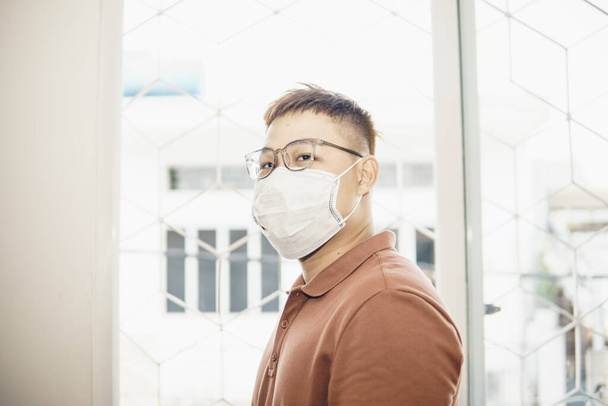Protection against coronavirus in workplace. Young asian man putting on hygienic face mask. shocked by 2019-nCoV or Covid 19 outbreak. studio shot - Foto, afbeelding