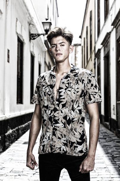 Portrait of young retro style man with shirt printed on old street. - Photo, Image