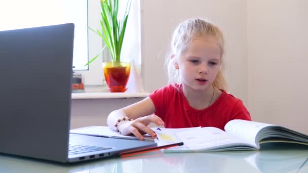 Distance learning online education. Schoolgirl studying at home with digital tablet and doing school homework. Training books and notebooks on table. - Πλάνα, βίντεο