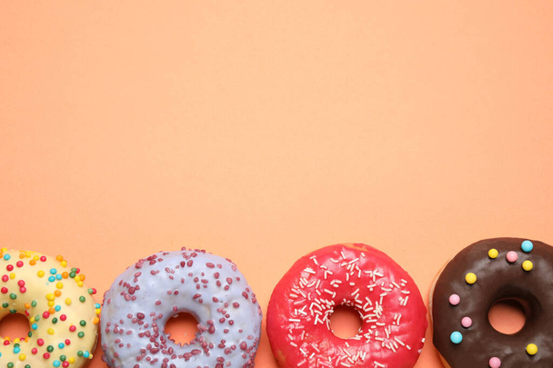 Delicious glazed donuts on orange background, flat lay. Space for text - Photo, image