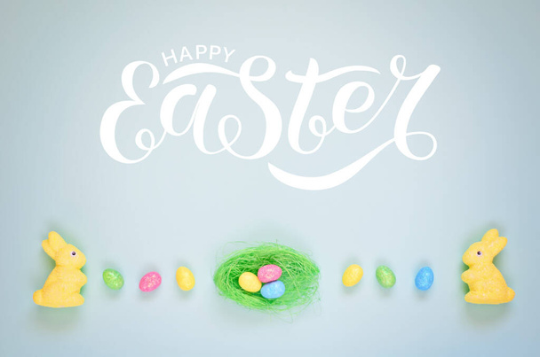 Easter holiday background with colorful shiny eggs and two yellow bunnies . Overhead shots. Happy easter text - Foto, Bild