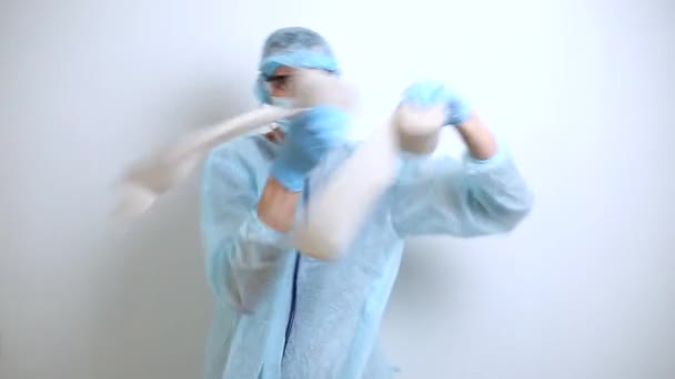 A doctor in a protective suit and mask is dancing fun holding toilet paper. - Metraje, vídeo