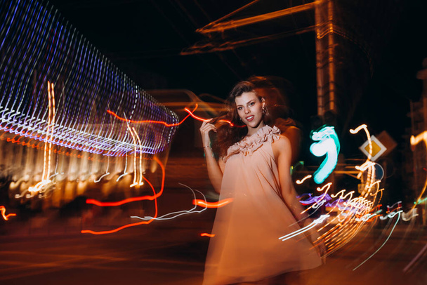Yazlık elbiseli genç bir kız gece şehirde dolaşıyor. - Fotoğraf, Görsel