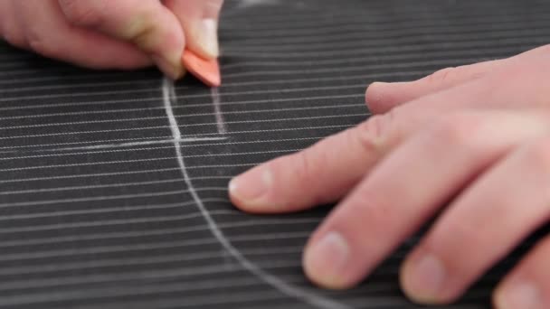 hand werken met naaipatroon in atelier. man op maat maken lijn, werken met krijt op persoonlijk bureau, het ontwikkelen van borduurpatroon op gestreepte zwarte stof - Video