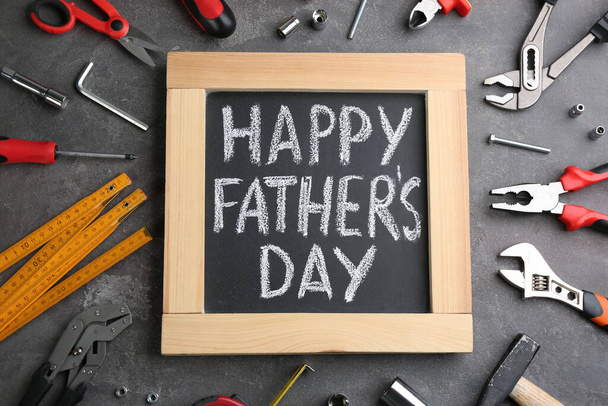 Blackboard with words HAPPY FATHER'S DAY and tools on grey stone background, flat lay - Zdjęcie, obraz