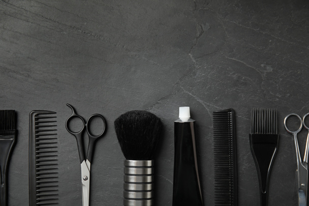 Профессиональные инструменты для окрашивания волос на черном каменном фоне, плоская укладка. Пространство для текста
 - Фото, изображение