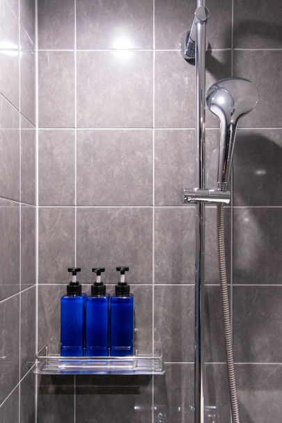 Body Wash, Shampoo e Condicionador são embalados em garrafas azuis no banheiro
 - Foto, Imagem
