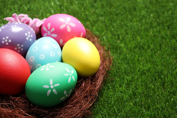 Colorful Easter eggs in decorative nest on green grass, closeup. Space for text - Foto, immagini