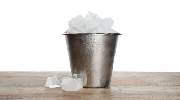 Metal bucket with ice cubes on wooden table against white background - Valokuva, kuva