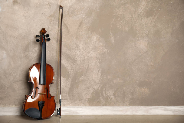 Classic violin and bow near beige wall. Space for text - Foto, afbeelding
