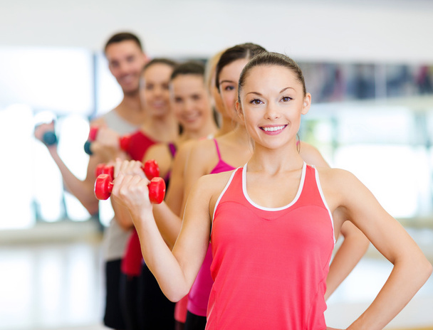 Group of smiling people with dumbbells in the gym - Foto, Bild