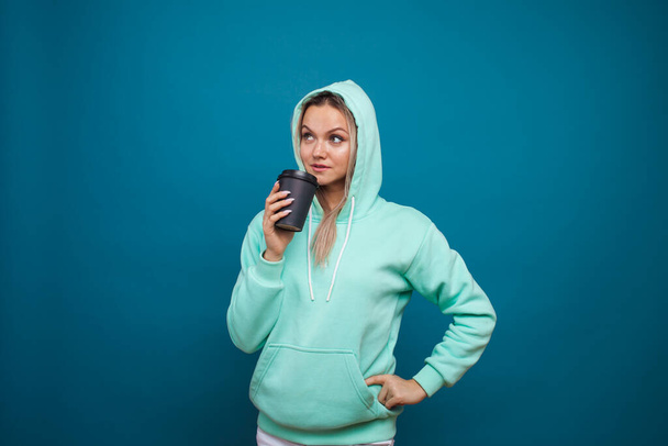 Warming drinks for autumn and winter. Stylish trendy hipster girl in a blue hoodie - Foto, Bild