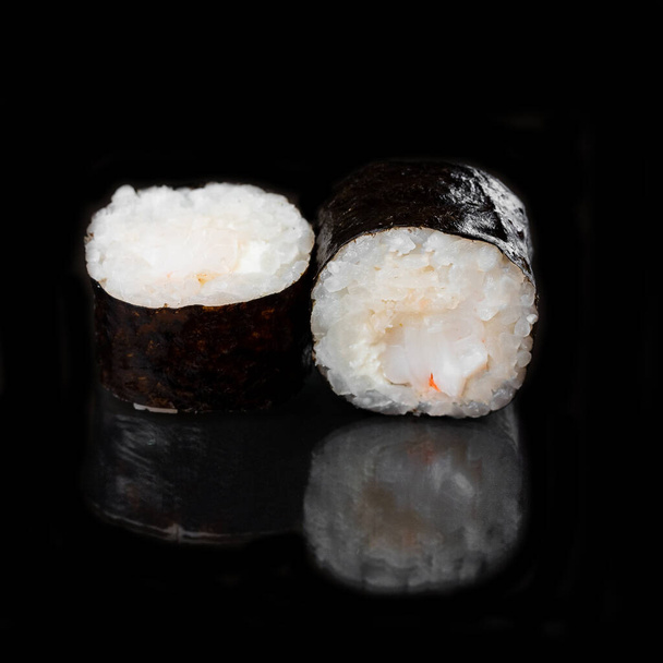 μαύρο νόρι σούσι ρολά με σολομό και λευκό ρύζι με τυρί κρέμα σε μαύρο τραπέζι φόντο - Φωτογραφία, εικόνα