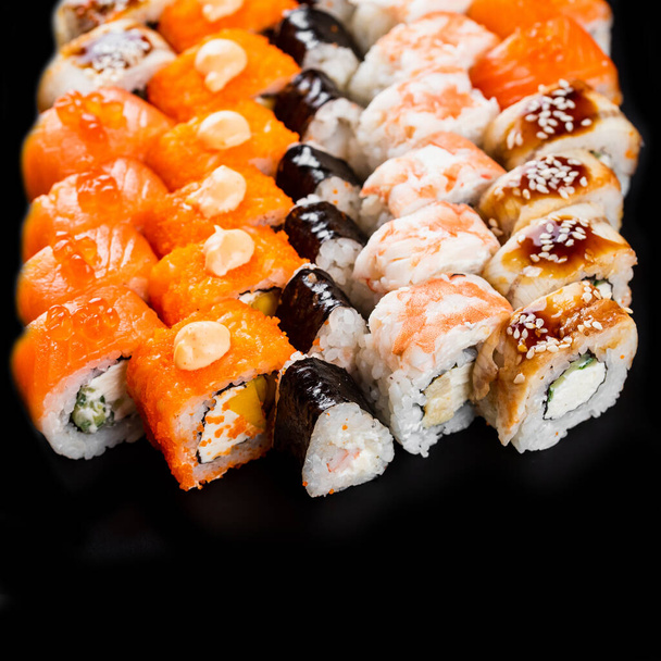 νόστιμα χρωματιστά διαφορετικά ρολά σούσι που με σολομό, γαρίδες και καπνιστό χέλι με τυρί κρέμα σε μαύρο πιατέλα - Φωτογραφία, εικόνα