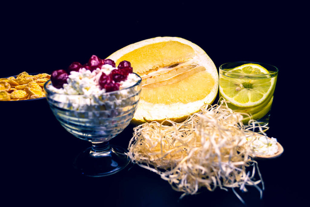 творог в стеклянной тарелке, наполовину помело, стакан воды с лимоном, деревянные стружки, хлопья
 - Фото, изображение