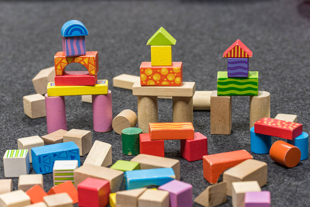 torres hechas de bloques de madera de colores dispuestos en un piso gris
 - Foto, imagen