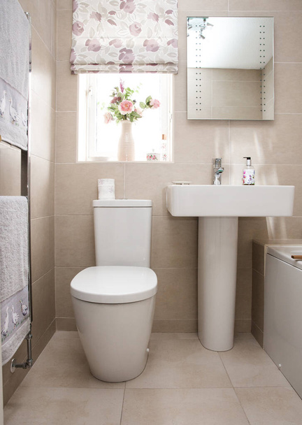 Un intérieur de maison de style cottage ou salle de bain carrelée contemporaine avec salle de bain blanche comprenant WC et lavabo
 - Photo, image