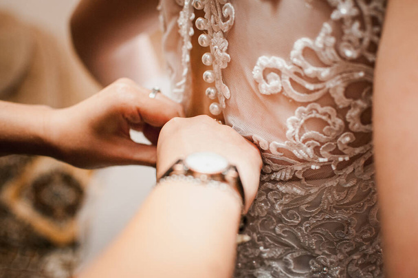 Bridesmaids assist bride to wear wedding dress - 写真・画像