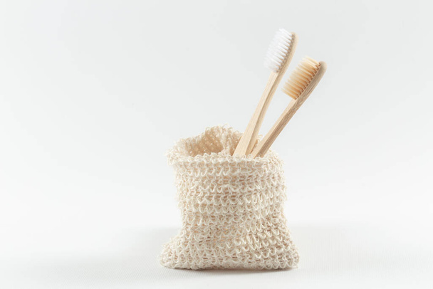 two natural wood toothbrushes lie in a row in an environmental bag. zero waste. on white background. - Photo, Image