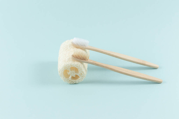 Two toothbrushes lie on a natural environmental loofah, designed for the body, on a white background - Fotoğraf, Görsel