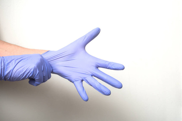 closeup of hands of doctor wearing a latex gloves to protect against the coronavirus pandemic on white background - Фото, изображение