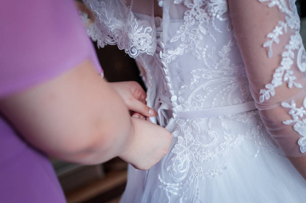 Las damas de honor ayudan a la novia a usar vestido de novia
 - Foto, imagen