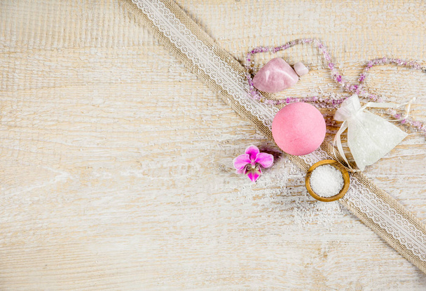 Bola de baño rosa con flor de orquídea y sal de baño sobre fondo de madera clara con espacio para copiar. Concepto de terapia. Tomar un baño relajante
. - Foto, Imagen