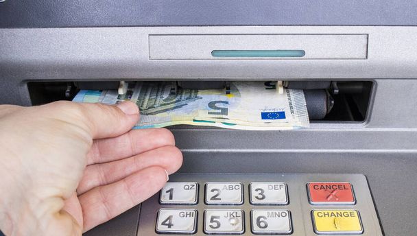 ATMの銀行のマシンからお金を取って、女性の手を閉じます。給料日の概念. - 写真・画像