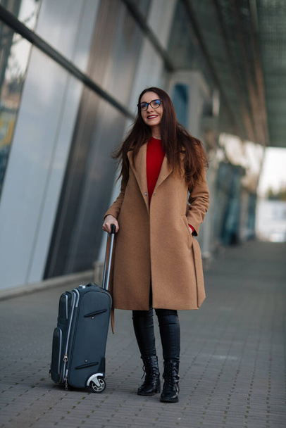 Travel, business trip. People and technology concept - happy young woman with travel bag on city street. - Valokuva, kuva