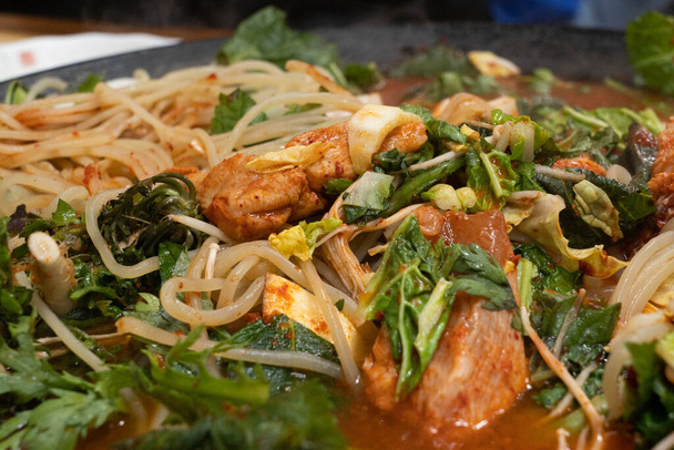Korean spicy chicken stir fry, Dak Galbi being boiled on a large hot pot with noodles and vegetables. - Photo, Image