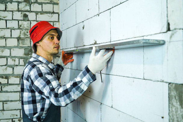 builder pressing construction ruler to interior wall checking its quality - Zdjęcie, obraz