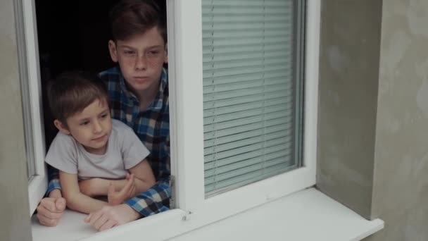Dzieci podczas kwarantanny wyjrzyj przez okno z nudnym spojrzeniem. - Materiał filmowy, wideo