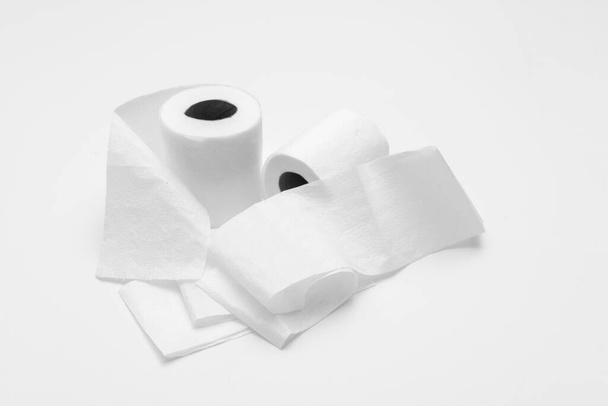 Two rolls of white toilet paper on white background, partly unrolled, viewed from an angle - Photo, Image