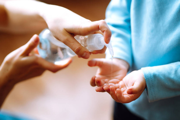 Hands with sanitizer gel. Mother and child using sanitize soap for hand coronavirus protection. Hygiene concept. Virus and illness protection, hand sanitizer in quarantine city. - Photo, image