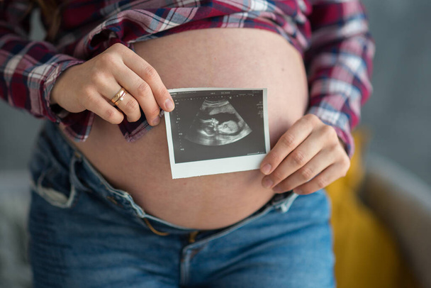 pregnant woman holding a picture of an ultrasound picture of a baby. happy motherhood concept - Fotografie, Obrázek