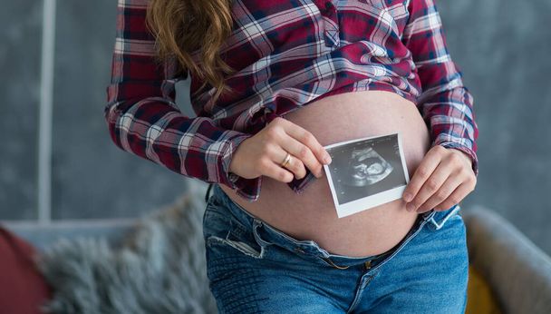 pregnant woman holding a picture of an ultrasound picture of a baby. happy motherhood concept - Photo, Image