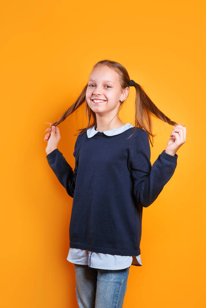 funny happy little girl in casual clothes having fun on yellow background - Foto, immagini
