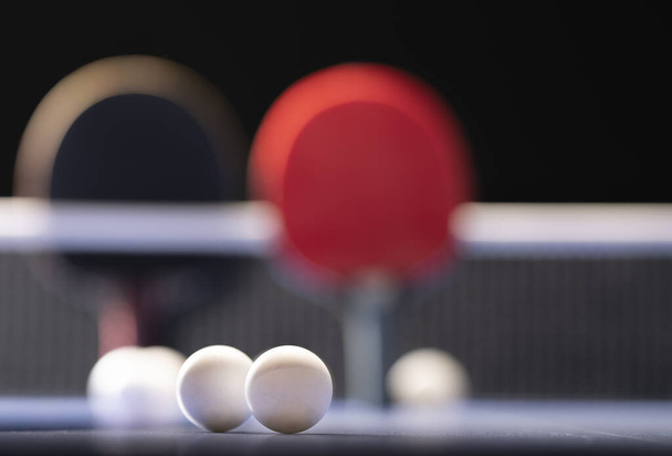 Две ракетки и мячи для настольного тенниса на синем столе с сеткой
. - Фото, изображение