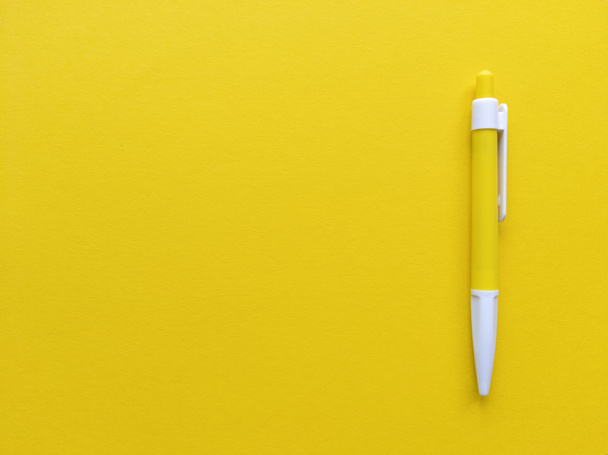 Yellow and white pen on yellow background. Minimalistic flat lay with copy space. Stock photo. - Фото, изображение