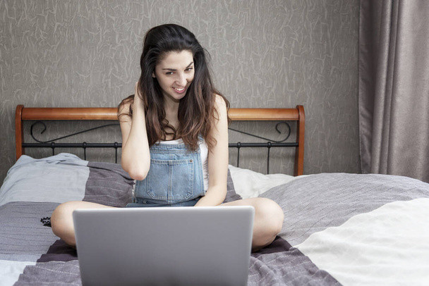 Młoda kobieta pracuje w domu w laptopie. Bloger jest na żywo. Kwarantanna podczas pandemii koronawirusowej. - Zdjęcie, obraz