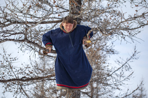Residentes del extremo norte, el pasto de los Nenets, la morada de los pueblos del norte de Yamal, joven cazador colgado de un árbol
 - Foto, Imagen
