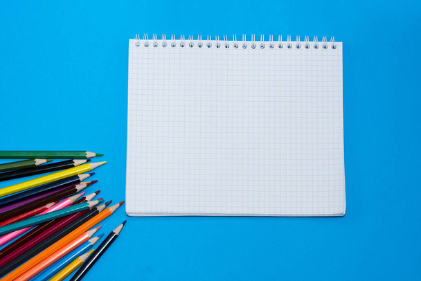 color pencils for drawing and notebook on a blue background - Foto, afbeelding
