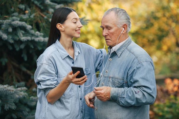 Girl teaching her grandfather how to use a phone - Valokuva, kuva