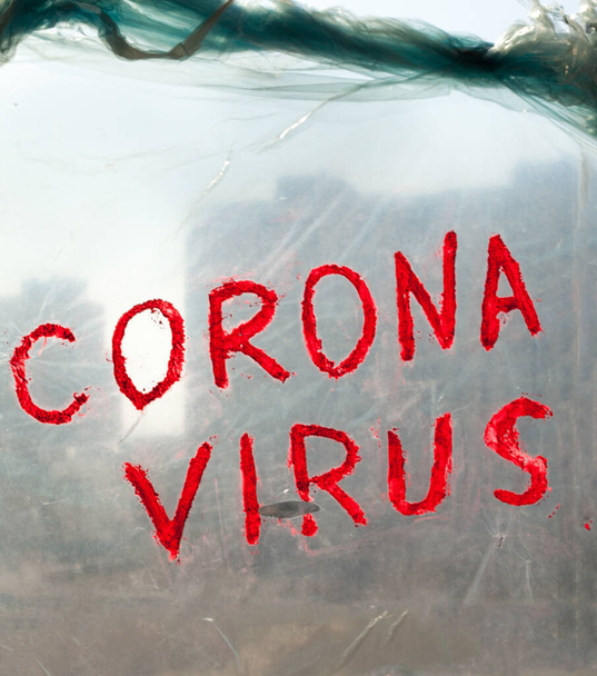 窓のポリテン表面にコロナウイルスの碑文。コロナウイルス(Covid-19)疾患の発生. - 写真・画像
