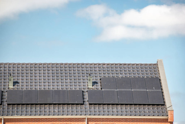Newly build houses in the Netherlands with solar panels attached on the roof against a sunny sky Close up of new building black solar panels - Photo, Image
