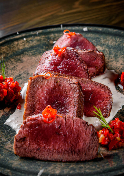  Juicy sliced steak medium rare beef in plate on wooden table background - Foto, Imagem